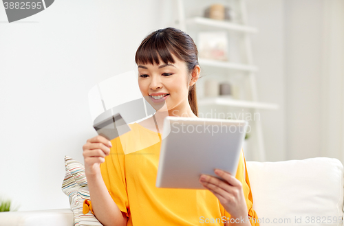 Image of happy asian woman with tablet pc and credit card