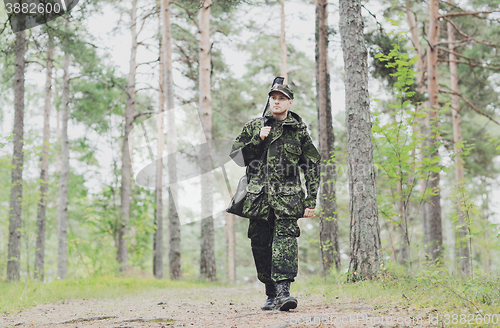 Image of young soldier or hunter with gun in forest