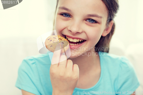 Image of smiling little girl eating cookie or biscuit