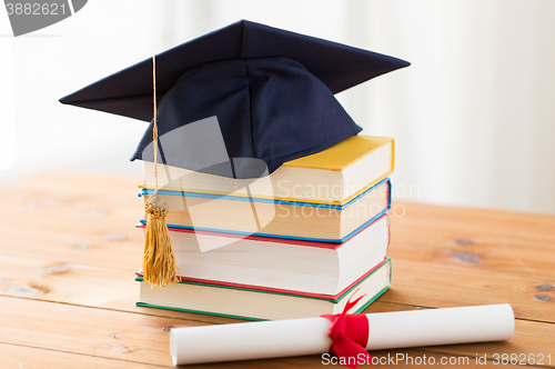 Image of close up of books with diploma and mortarboard