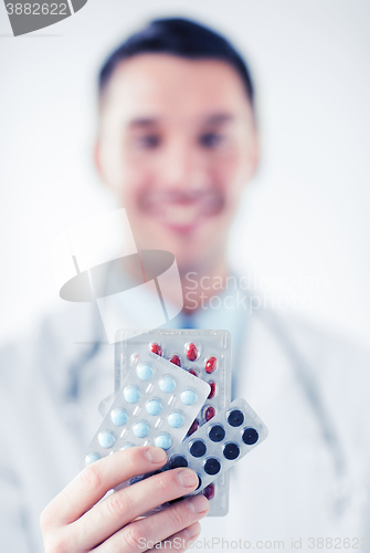 Image of male doctor with packs of pills