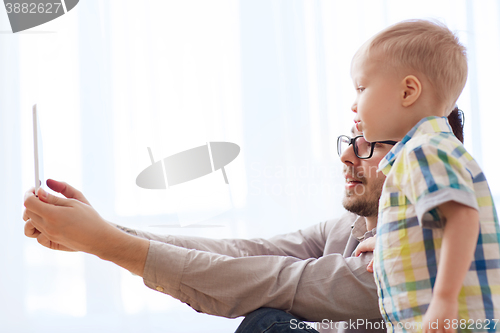 Image of father and son with tablet pc playing at home