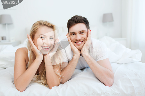 Image of happy couple lying in bed at home