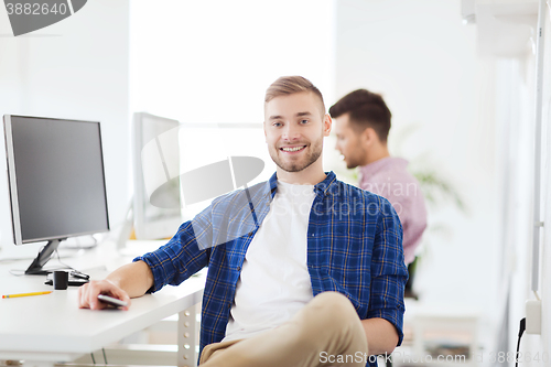 Image of happy creative man with cellphone at office