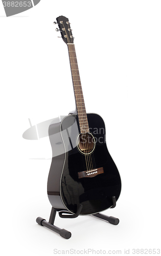 Image of Black acoustic guitar on stand, isolated