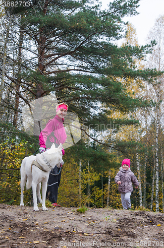 Image of Granny with her granddaughter and a dog walk in autumn Park  