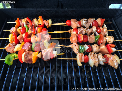 Image of Outdoor grill with meat and vegetable skewers