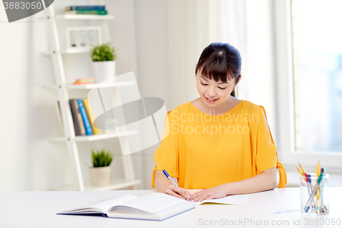 Image of happy asian young woman student learning at home