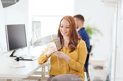 Image of woman with earphones and smartphone at office