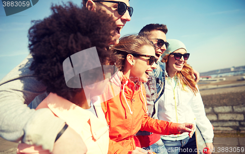 Image of smiling friends in sunglasses laughing on street