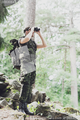 Image of soldier with binocular and backpack in forest