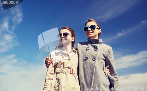 Image of happy little girls in sunglasses hugging outdoors