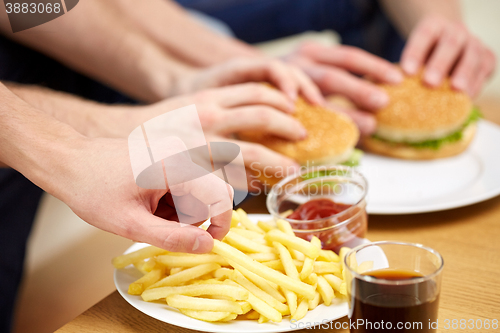 Image of close up of male hands with fast food on table