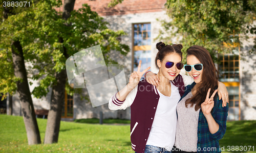 Image of smiling teenage girls in sunglasses showing peace