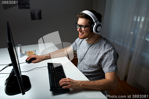 Image of man in headset playing computer video game at home