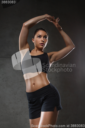 Image of young woman posing and showing muscles in gym