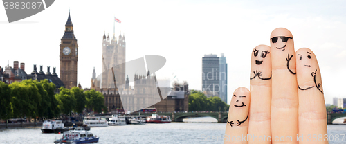 Image of close up of fingers with smiley faces over london