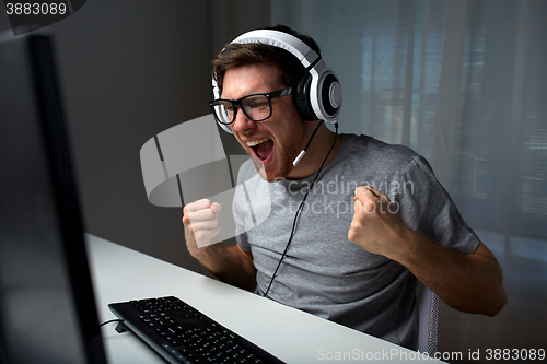 Image of man in headset playing computer video game at home