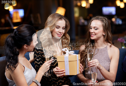 Image of happy women with champagne and gift at night club