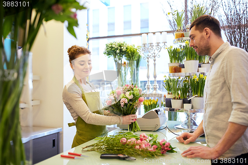 Image of smiling florist woman and man at flower shop