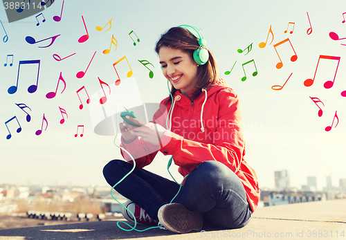 Image of happy young woman with smartphone and headphones