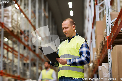 Image of man with clipboard in safety vest at warehouse