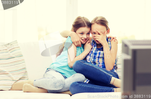 Image of scared little girls watching horror on tv at home