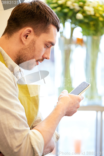 Image of florist man texting on smartphone at flower shop