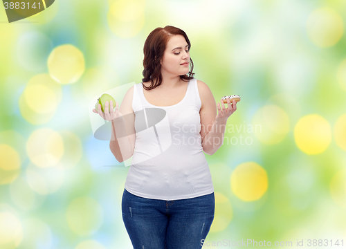 Image of young plus size woman choosing apple or cookie