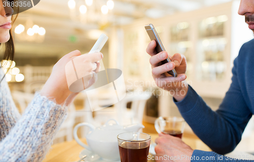 Image of close up of couple with smartphones at cafe