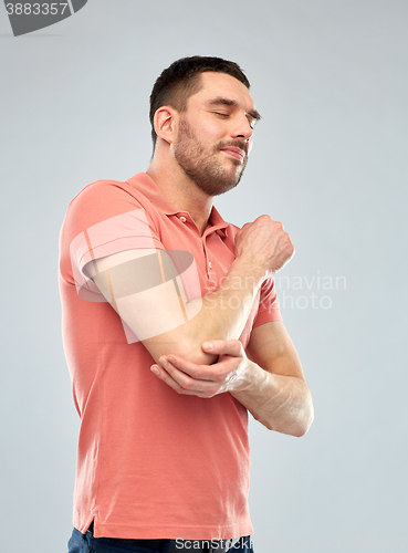 Image of unhappy man suffering from pain in hand