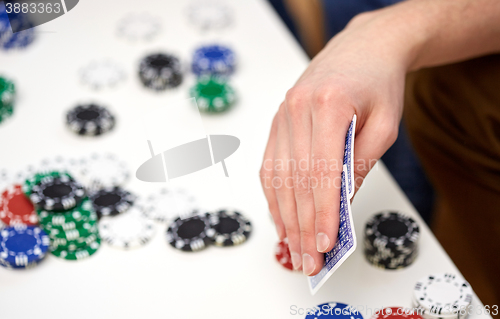 Image of close up of male hand with playing cards and chips