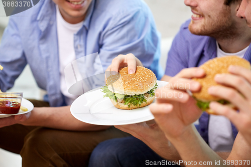 Image of close up of friends eating hamburgers at home