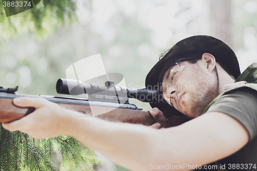 Image of young soldier or hunter with gun in forest