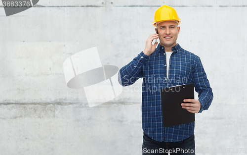Image of smiling builder in helmet calling on smartphone