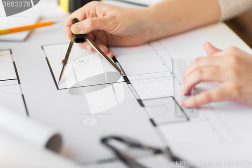 Image of close up of hands with compass measuring blueprint