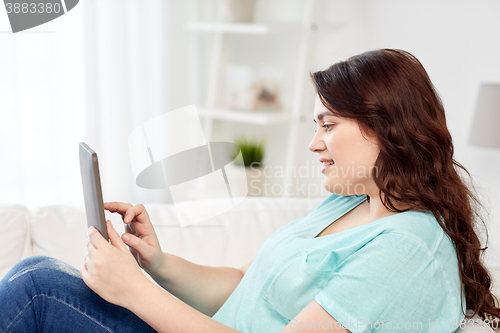 Image of happy young plus size woman with tablet pc at home