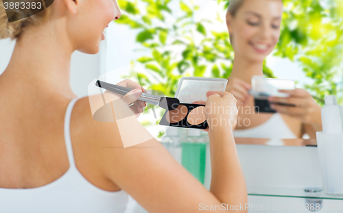 Image of woman with makeup brush and foundation at bathroom
