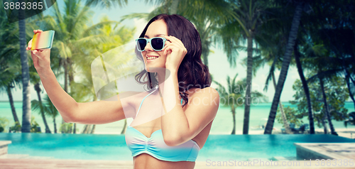 Image of woman in swimsuit taking selfie with smatphone