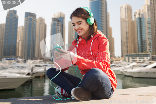 Image of happy young woman with smartphone and headphones