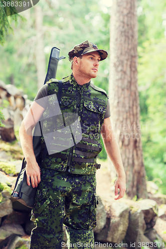 Image of young soldier or hunter with gun in forest