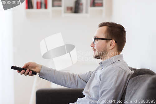 Image of smiling man with tv remote control at home