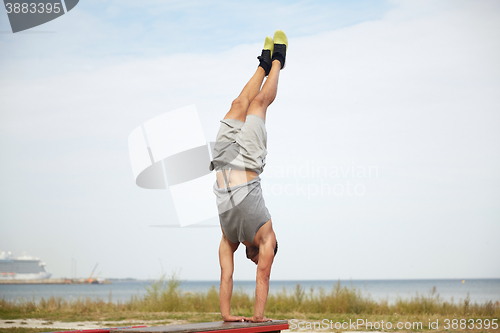 Image of young man exercising on bench outdoors