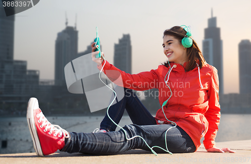 Image of happy young woman with smartphone and headphones