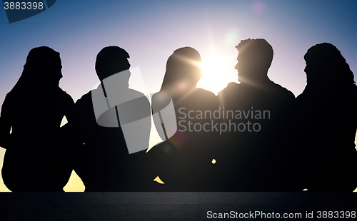 Image of silhouettes of friends sitting on stairs over sun