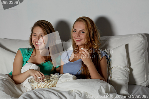 Image of happy friends with popcorn and watching tv at home