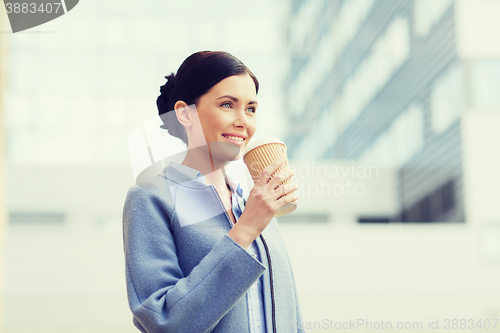 Image of smiling woman drinking coffee in city