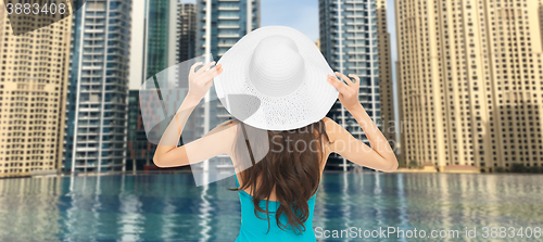 Image of woman in sun hat from back over dubai city pool