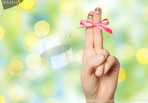 Image of close up of two fingers tied by pink bow knot