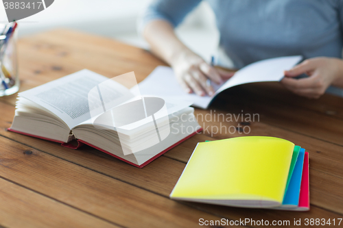 Image of close up of student with book and notebook at home